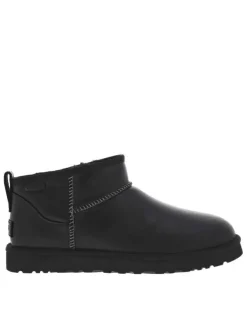 Boots en cuir noires à talon plat avec des surpiqûres noires et blanches