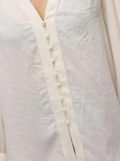 Chemisier écru avec un grand col v et fermeture avec boutonnière nacrée