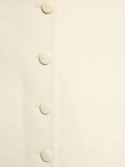 Jupe courte écrue à coupe droite pourvue de multiples boutons à l'avant