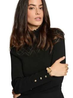 Pull noir pourvu d'un col montant et de manches longues avec boutons dorés