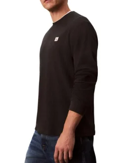 Pull noir uni texturé avec un petit patch brodé et à col rond