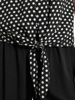 Top noir à pois avec une coupe droite un col v et des manches courtes