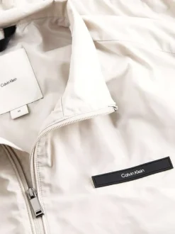Veste blanche légère avec un aspect satiné un col montant et des poches